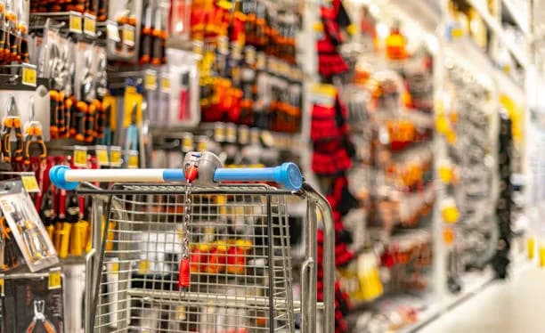 Panier de magasinage vide devant un mur d’outils à main dans une quincaillerie