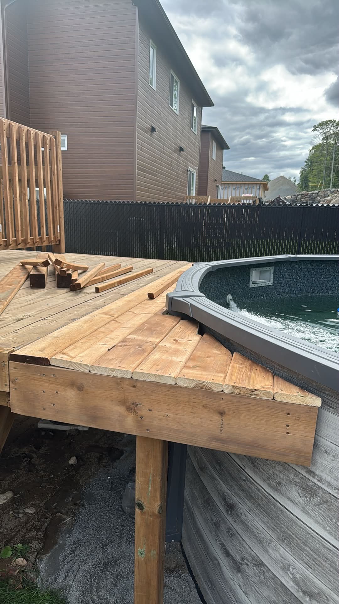 Terrasse en bois traité en construction autour d’une piscine hors terre, avec des planches et des retailles posées sur le platelage