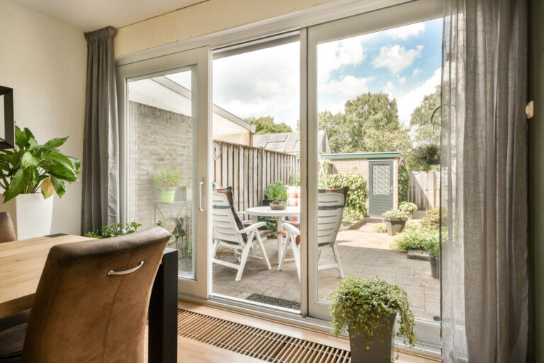 Porte patio coulissante en PVC blanc vue de l’intérieur, ouvrant sur une terrasse